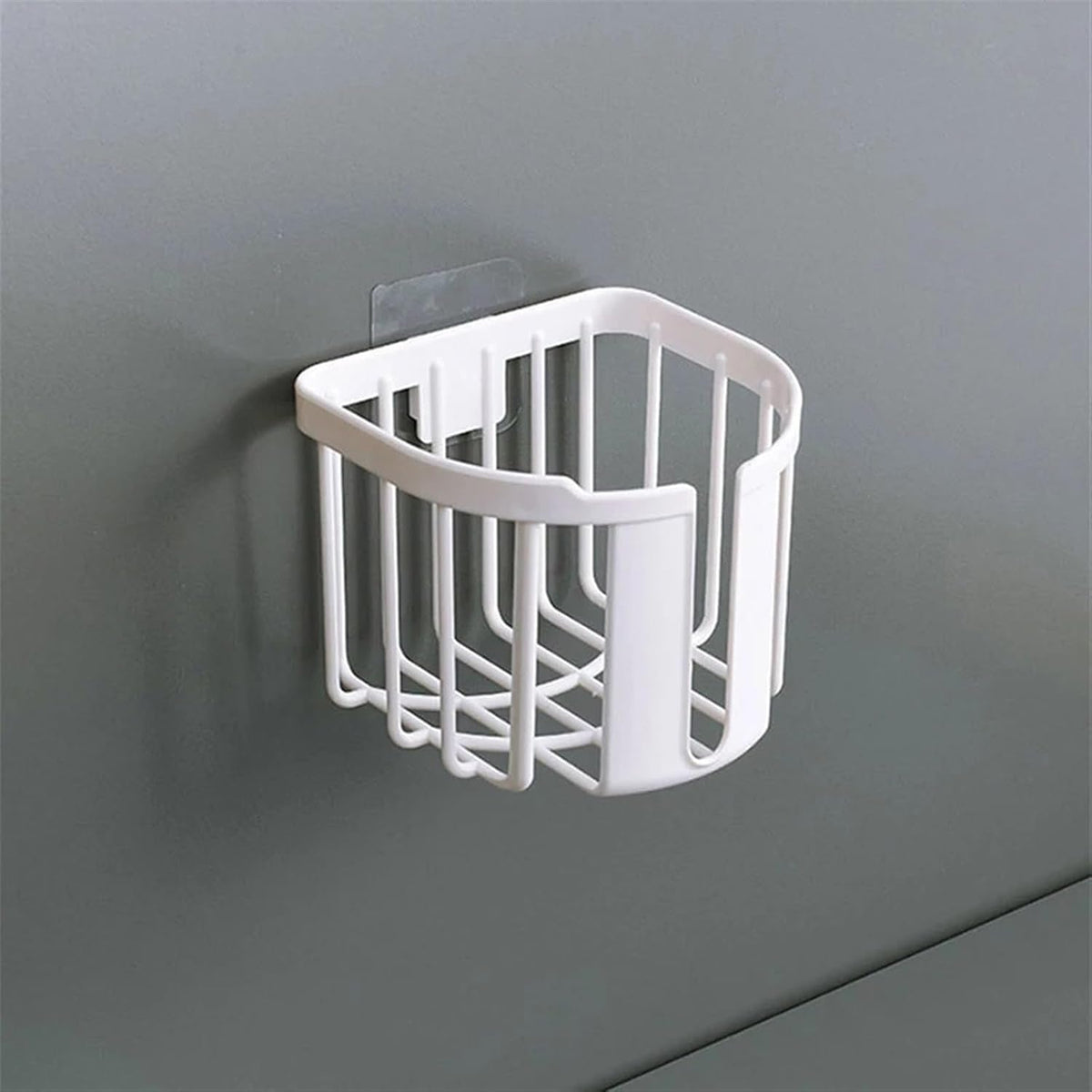 A white plastic toilet paper holder with vertical slats and a clear adhesive hook is mounted on a gray wall.