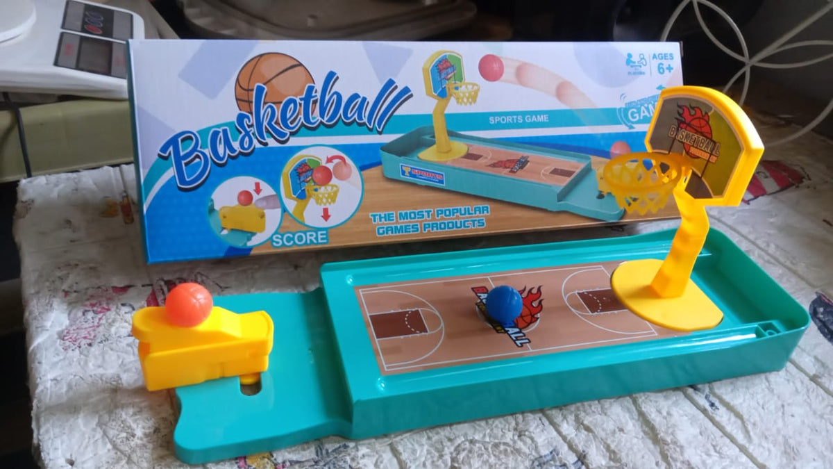 The miniature basketball game and its product box displayed on a patterned surface, with a blue ball on the court.