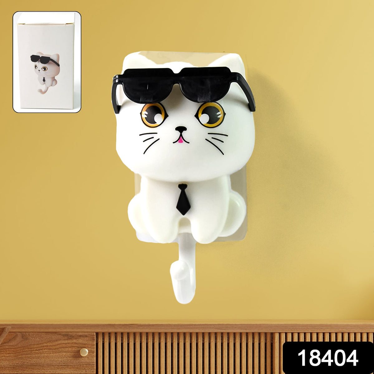 White cat-shaped wall hook with sunglasses and a tie on a yellow wall, with an inset showing packaging.