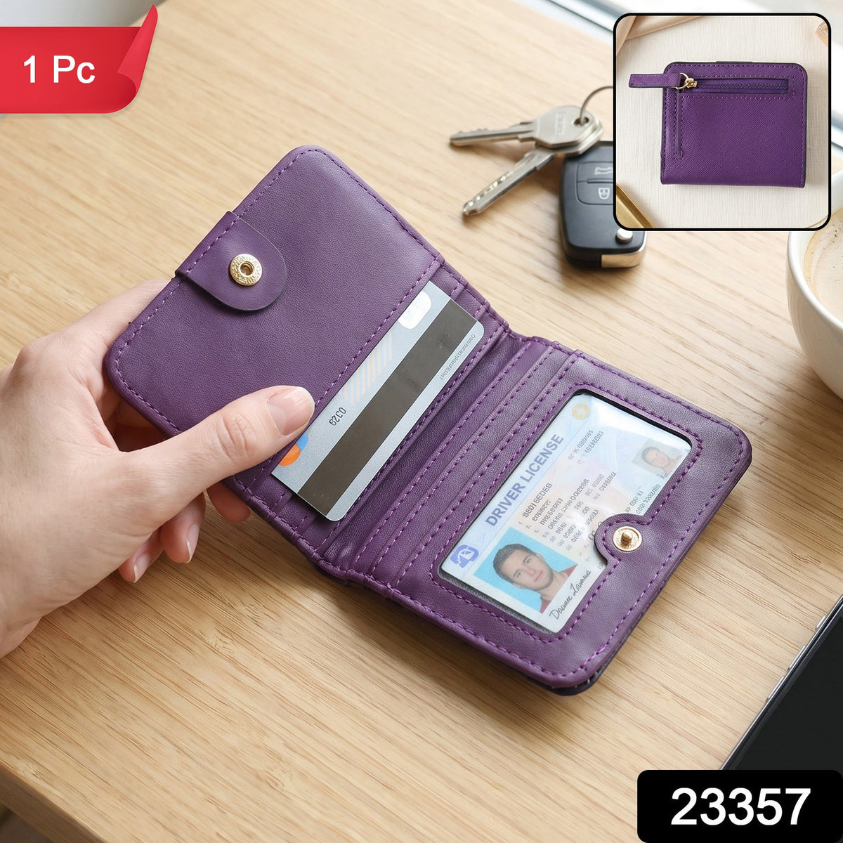 A hand holds an open purple bifold wallet with a credit card and driver's license inside, on a wooden table