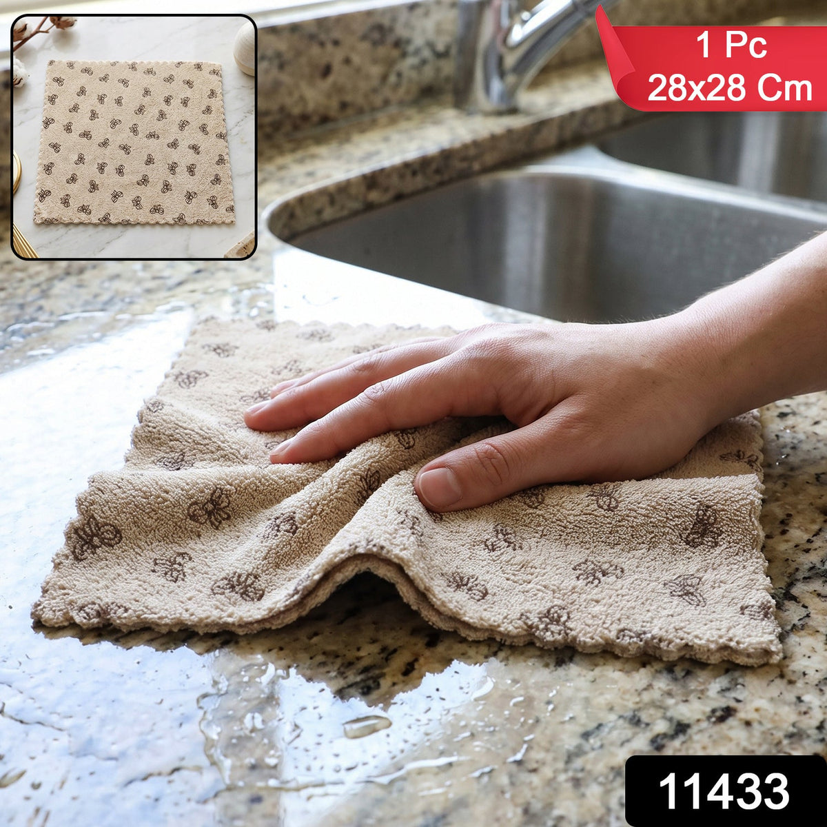 A hand wipes a wet granite countertop with a beige microfiber towel patterned with dark bows, next to a kitchen sink.