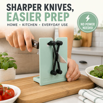 A person uses a mint green X-rod knife sharpener on a wooden cutting board with fresh vegetables nearby.