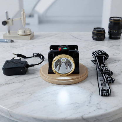 A black and gold headlamp with a solar panel, a charger, and a black and white head strap on a marble table.