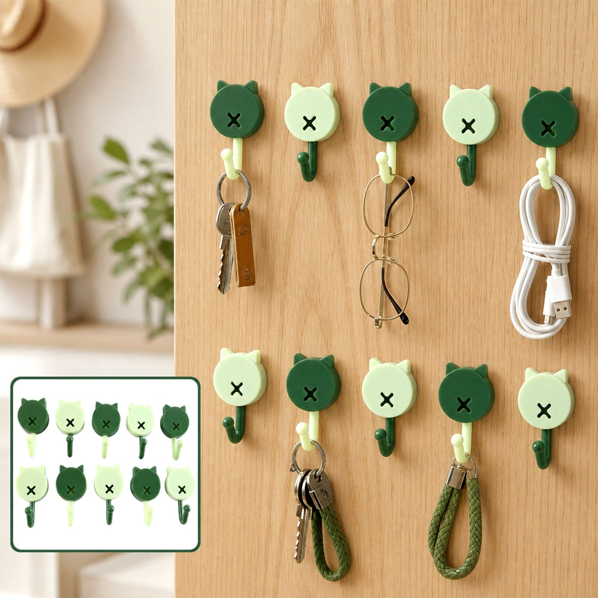 Ten cat-shaped wall hooks in dark and light green holding keys, glasses, and a charging cable on a wooden wall.