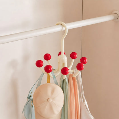 A cream multi-hook hanger with red ball tips, holding a light blue bag, a beige cap, and two scarves, hanging inside a white