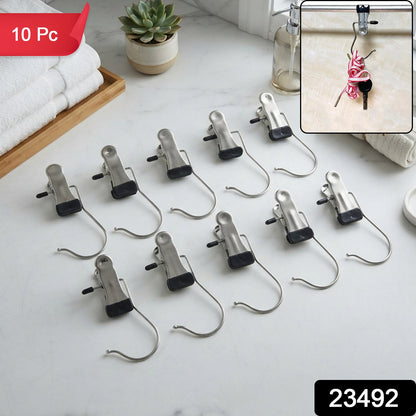 Ten metal clip hangers with black rubber tips are neatly arranged on a white marble countertop next to folded white towels