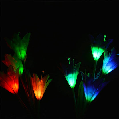 Several solar flower lights glow in various colors like red, orange, green, and blue in a dark setting.