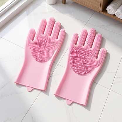 A pair of pink silicone scrubbing gloves lying flat on a light-colored tiled floor next to a cabinet.