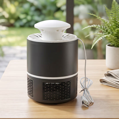 Black and white mosquito killer lamp with its USB cable on a wooden table with a folded cloth and plants.
