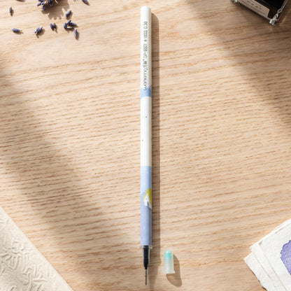 A white and blue pen refill with a small light blue cap on a wooden desk, surrounded by dried lavender.
