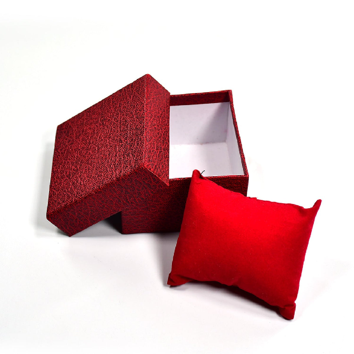 An open red textured gift box with its lid ajar, and a red velvet pillow placed next to it on a white background.
