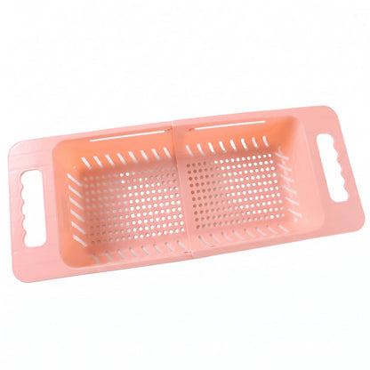 Pink plastic adjustable over-sink drain basket with perforated bottom and handles, extended to its full length.