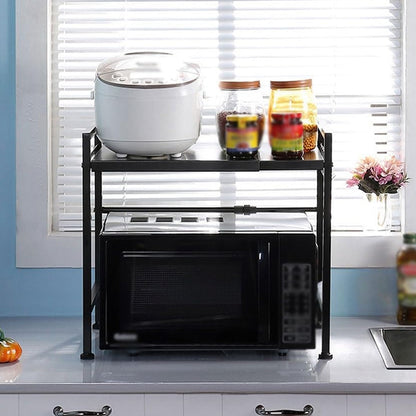 Black microwave on a black metal rack, with a rice cooker and jars on top, by a window with blinds.