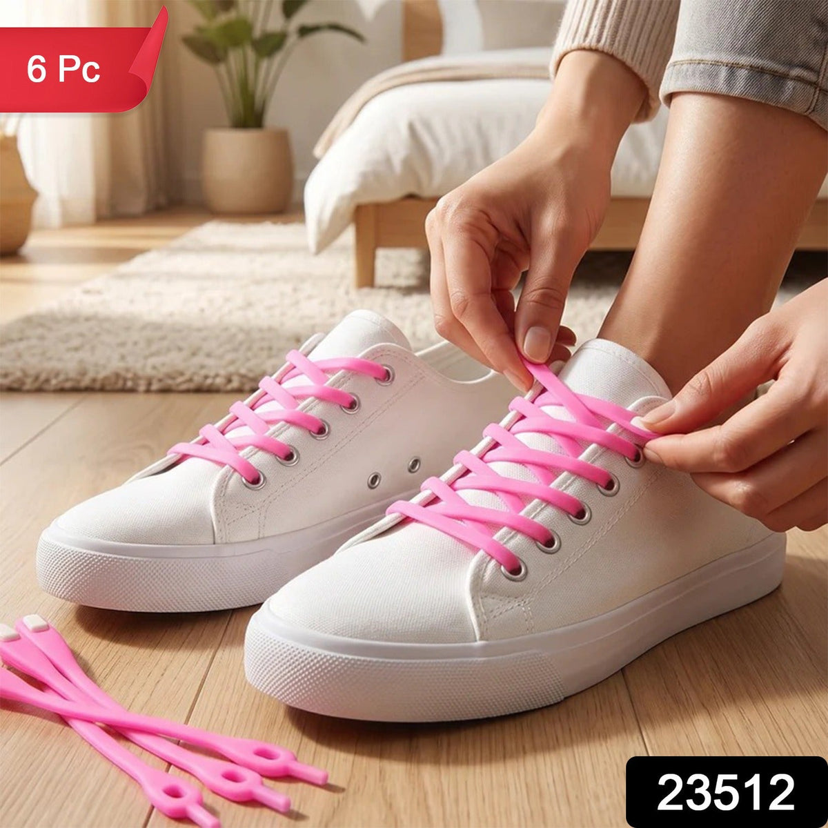 A person's hands lacing up white canvas shoes with bright pink silicone shoelaces, with extra laces on the floor. – view 2