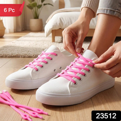 A person's hands lacing up white canvas shoes with bright pink silicone shoelaces, with extra laces on the floor. – view 2