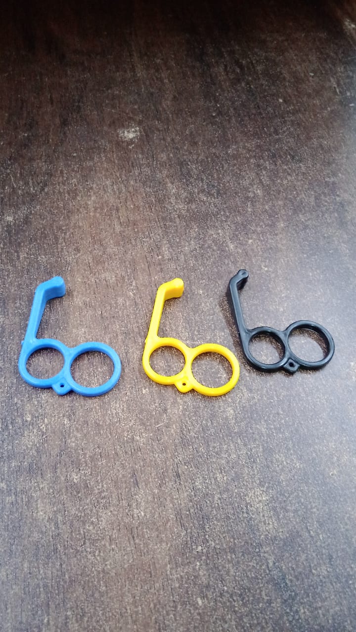 Three plastic finger ring phone holders in blue, yellow, and black are arranged on a dark wooden surface.
